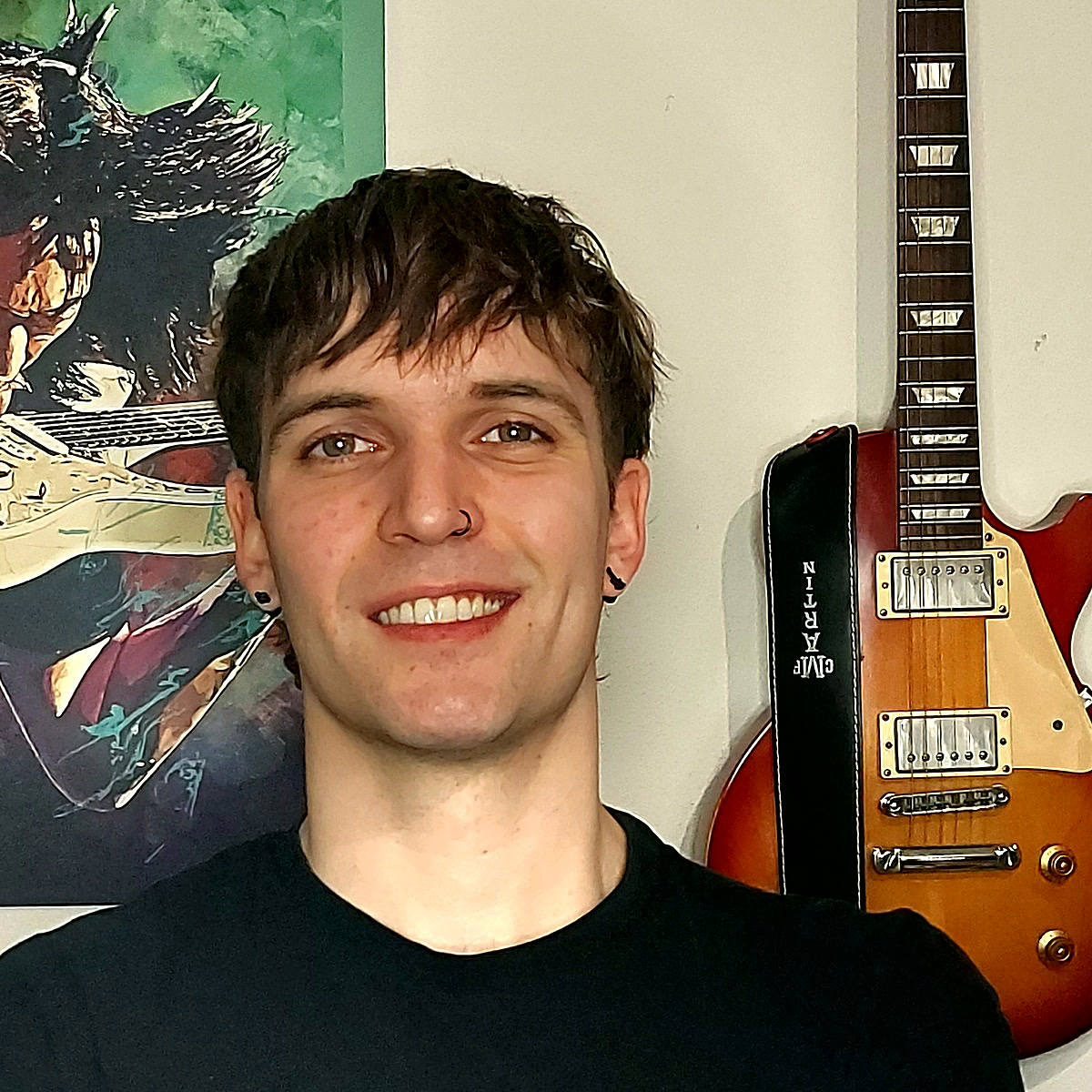 Rolo, smiling, in front of his guitar wall